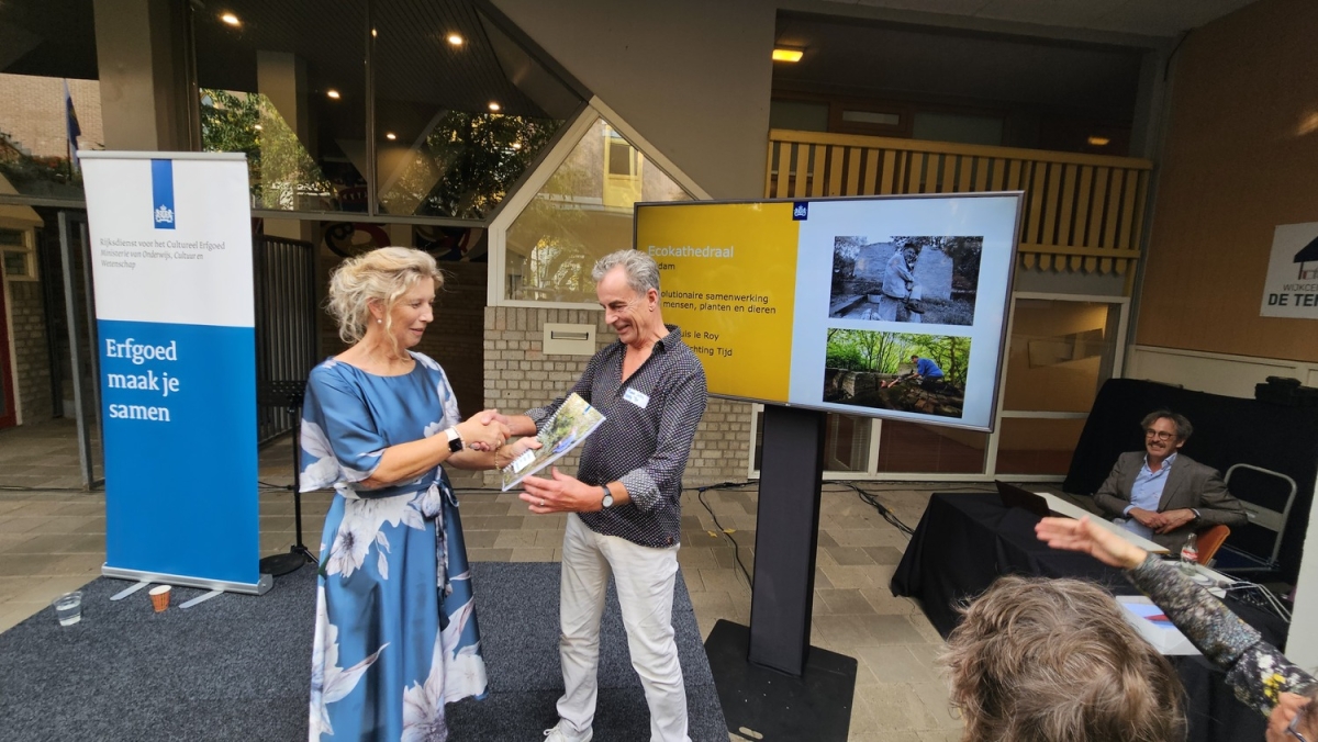 Marcel Prins ontvangt de bijbehorende documenten uit handen van Susan Lammers, algemeen directeur van de Rijksdienst voor het Culturele Erfgoed
